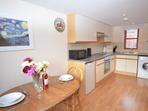 A modern kitchen with a dining area, a painting on the wall, and a clock. - 1 Bed in Gillingham (oc-cobco) (Kington Magna)