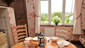 Una mesa de comedor con sillas, una cafetera y diferentes platos y utensilios.