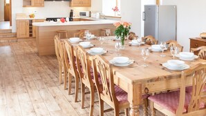 Een ruime keuken met houten kastjes, een centraal eiland en een eethoek voor zes personen.