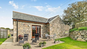 A stone house with a patio, outdoor seating, and a grassy yard. - 1 Bed in Helston (oc-boder) (Wendron)