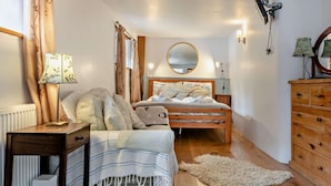 A bedroom with a bed, bedside table, lamp, mirror, dresser, and a rug. - 6 Bed in Winkleigh (oc-furfa) (Iddesleigh)