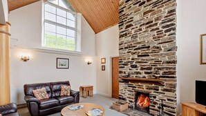 Ein gemütliches Wohnzimmer mit Kamin aus Stein, einer Ledersofa und einem runden Couchtisch aus Holz.