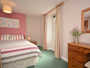 A bedroom with a bed, a dresser, a mirror, a window with curtains, and a wall with a floral painting. - 2 Bed in Wells (oc-vespe) (Wells)