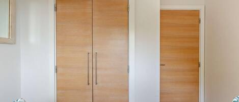 A room with two beds, a wooden wardrobe, and a mirror on the wall.