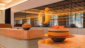Zona de recepción con diseño moderno, un amplio ventanal con un patrón circular distintivo y un mostrador con cuencos.