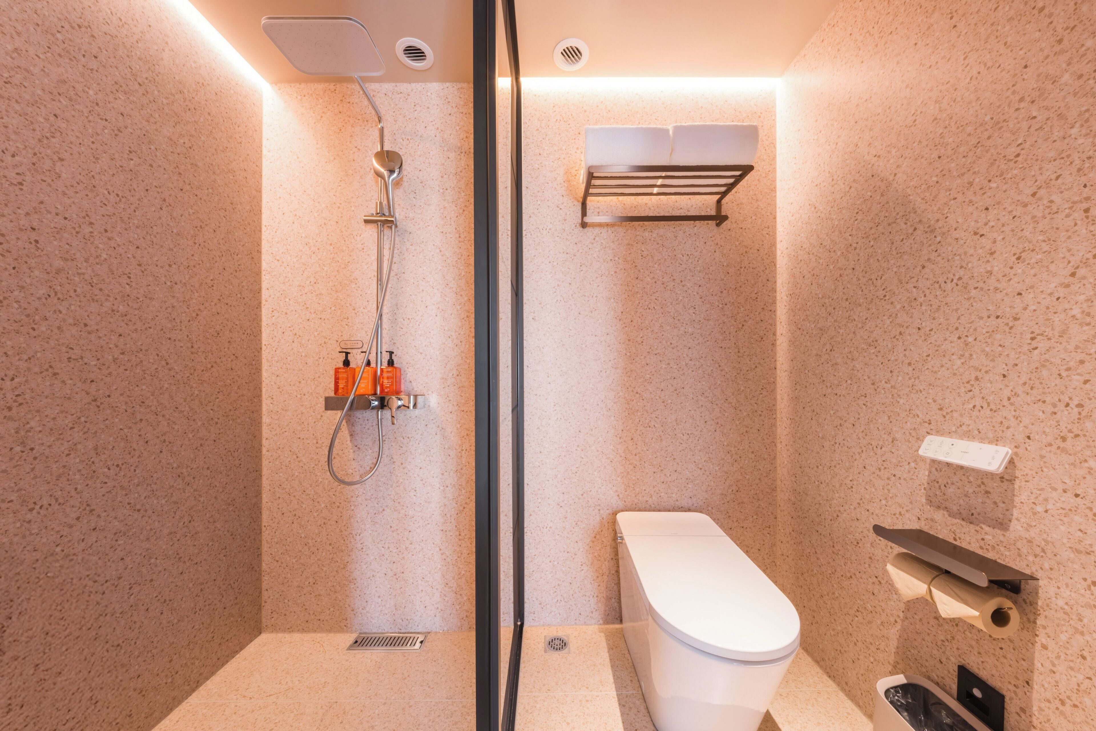 Un baño moderno con cabina de ducha de vidrio, inodoro y barra para toallas.