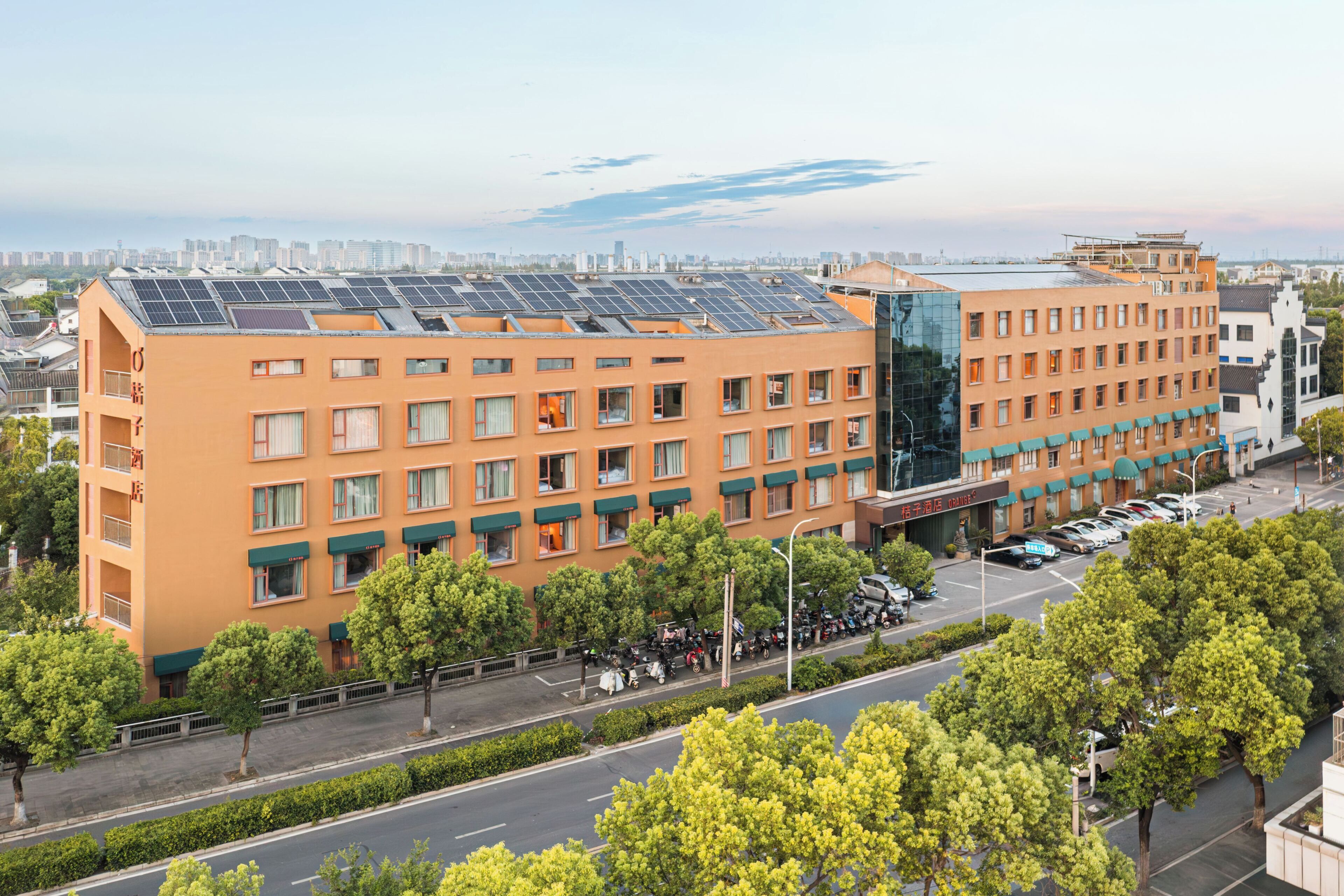 A multi-story hotel with a flat roof, large windows, and a parking lot.