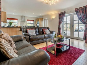 Ein modernes Wohnzimmer mit einem Ledersofa, einem Glastisch und einem roten Teppich.