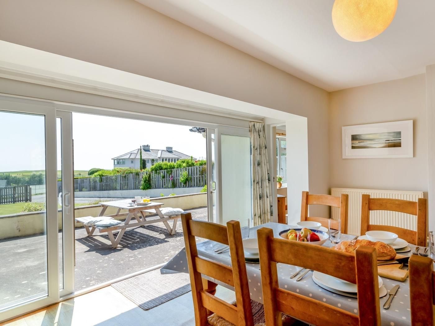 A dining area with a table set for two, a view of the outside, and a framed picture on the wall.