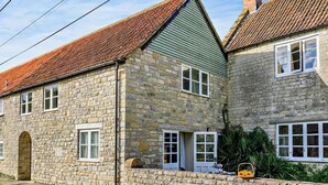 A stone building with a sloped roof, multiple windows, and a small porch area. - 1 Bed in Yeovil (oc-poloc) (West Camel)