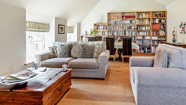 A modern living room with a large bookshelf, two sofas, a coffee table, and a dining table. - 1 Bed in Yeovil (oc-poloc) (West Camel)