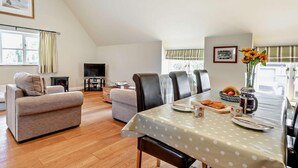 A dining area with a table set for four, a sofa, a television, and a fireplace. - 1 Bed in Yeovil (oc-poloc) (West Camel)