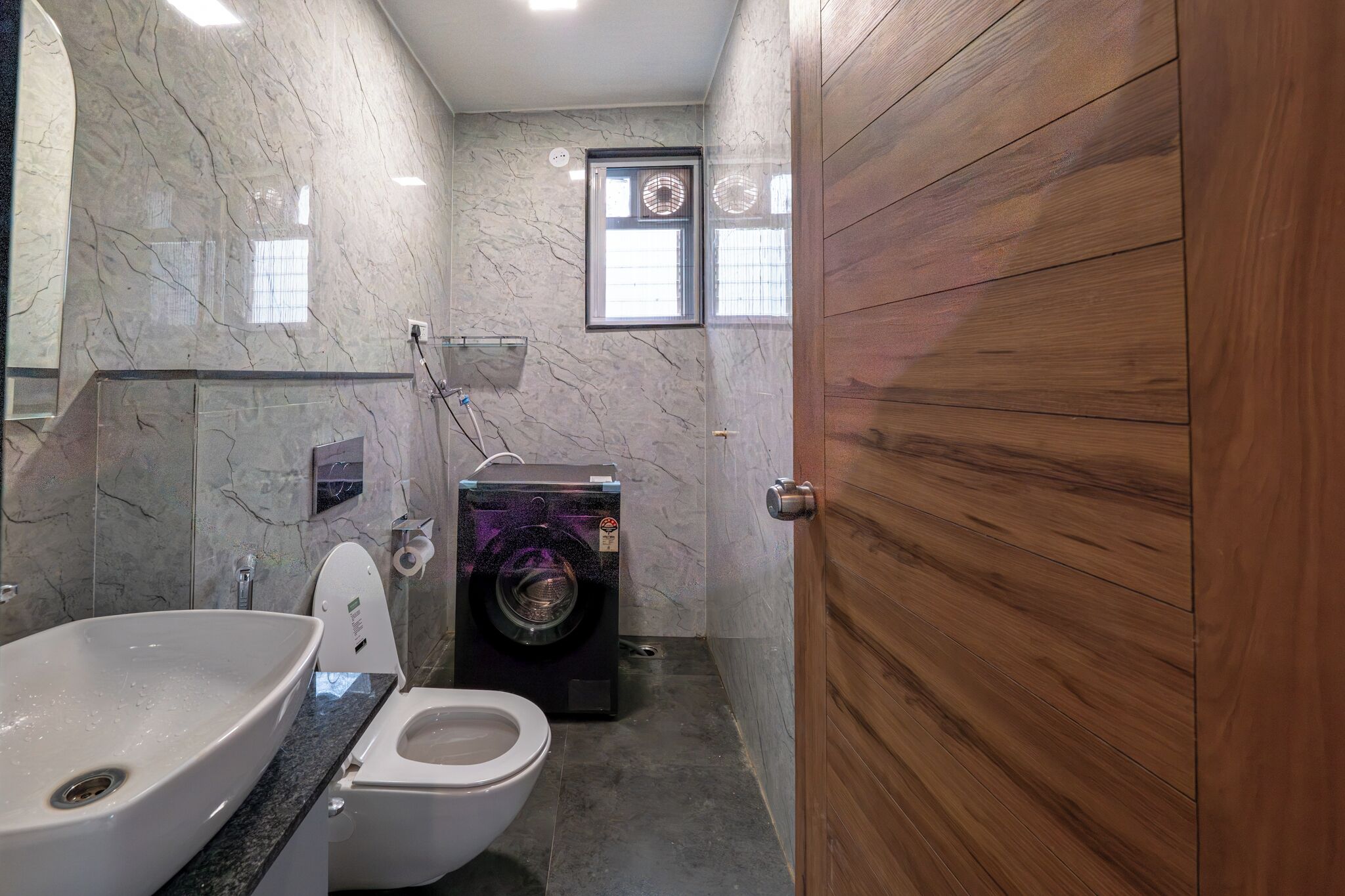 Casa de banho compacta com lavatório, sanita e máquina de lavar roupa.