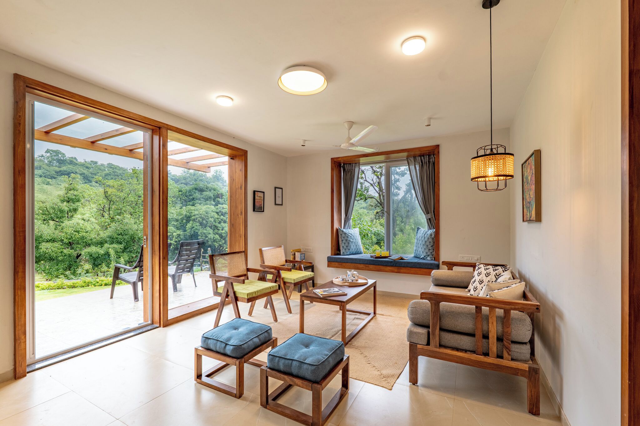 A spacious living area with large windows, a ceiling fan, and a wooden coffee table.
