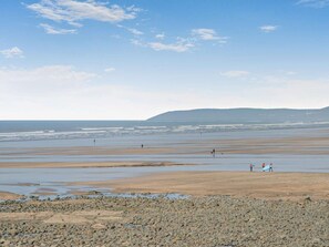 A beach with a rocky foreground, a wide expanse of sand, and a distant mountain range. - 1 Bed in Bideford (oc-poinb) (Westward Ho!)