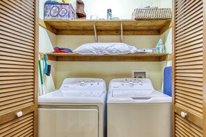 A laundry room with two front-loading washing machines, wooden shelves above, and a hanging rack. - Bird Hallar - "Cozy, Peaceful, Secluded Cabin in the Smokies" (Gatlinburg)