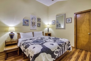 A bedroom with a bed, bedside tables, lamps, and framed artwork on the walls. - Bird Hallar - "Cozy, Peaceful, Secluded Cabin in the Smokies" (Gatlinburg)