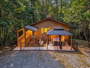 A wooden cabin with a covered deck, a hot tub, and a staircase leading to an upper level. - Bird Hallar - "Cozy, Peaceful, Secluded Cabin in the Smokies" (Gatlinburg)