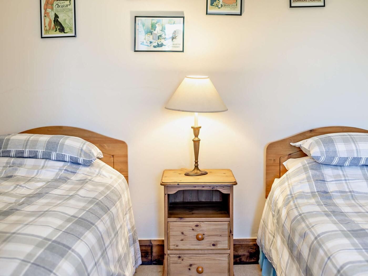 Une chambre avec deux lits, une table de chevet avec une lampe et des œuvres d’art murales.