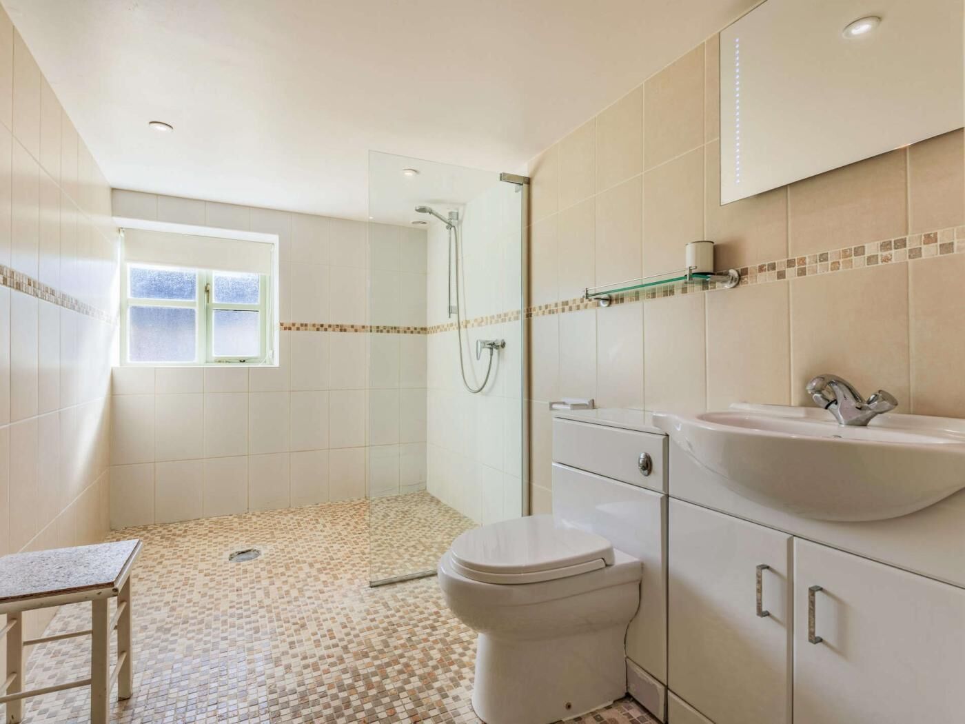 A bathroom with a shower, toilet, sink, and a window.