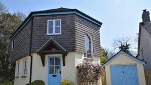 Ein zweistöckiges Haus mit blauer Tür, einer kleinen Veranda und einer Garage.