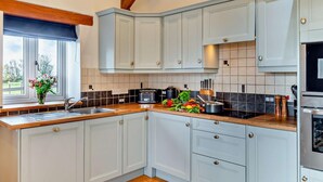 A modern kitchen with light blue cabinets, a wooden countertop, and a built-in oven. - 1 Bed in Bideford (oc-linne) (Hartland)