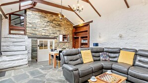 A cozy living room with a stone wall, wooden beams, a leather sofa, and a chess table. - 1 Bed in Camelford (oc-hopar) (Lanteglos)