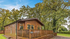 A wooden cabin with a balcony, surrounded by trees. - 3 Bed in Okehampton (oc-06199) (Okehampton Hamlets)