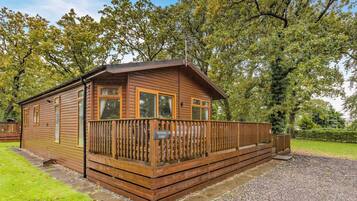 Une cabane en bois dotée d’un balcon, entourée d’arbres.