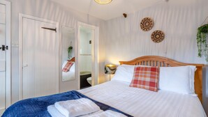 Een slaapkamer met een bed, een spiegel, een bedlampje en een wandlamp.