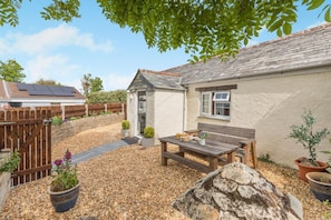 Ein Haus mit Garten, einem Holzzaun, einer Bank und einem kleinen Schuppen.
