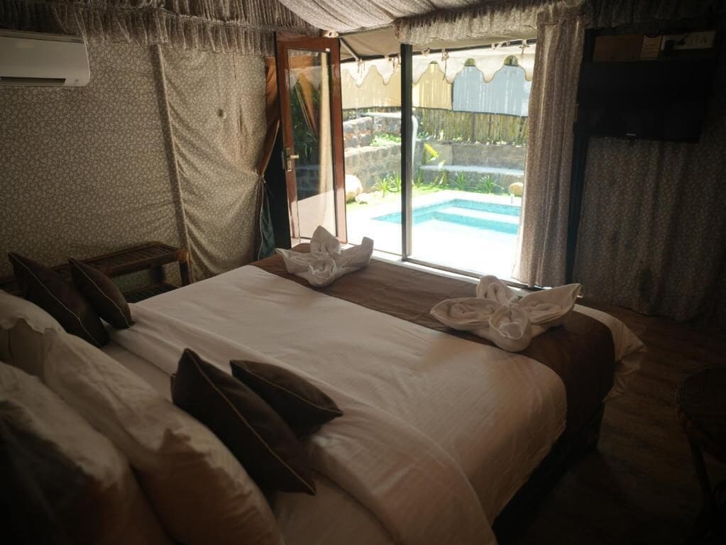 Quarto com uma cama, uma mesa pequena e vista para uma piscina ao ar livre.