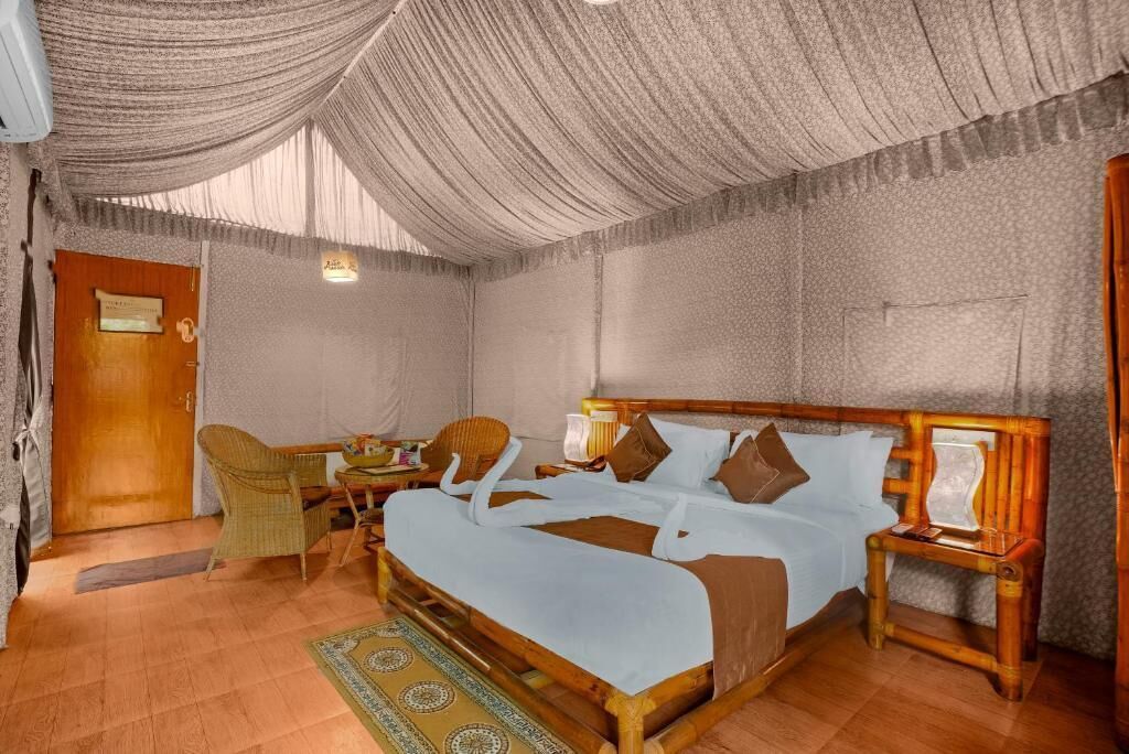 A room with a bed, a chair, a small table, and a door.