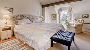 Een slaapkamer met een groot bed, een nachtkastje, een stoel en een raam met uitzicht.