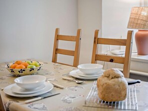 A dining table with a bowl of fruit, white plates, a loaf of bread, and a lamp in the background. - 1 Bed in Dorchester (oc-manje) (Frome Saint Quintin)
