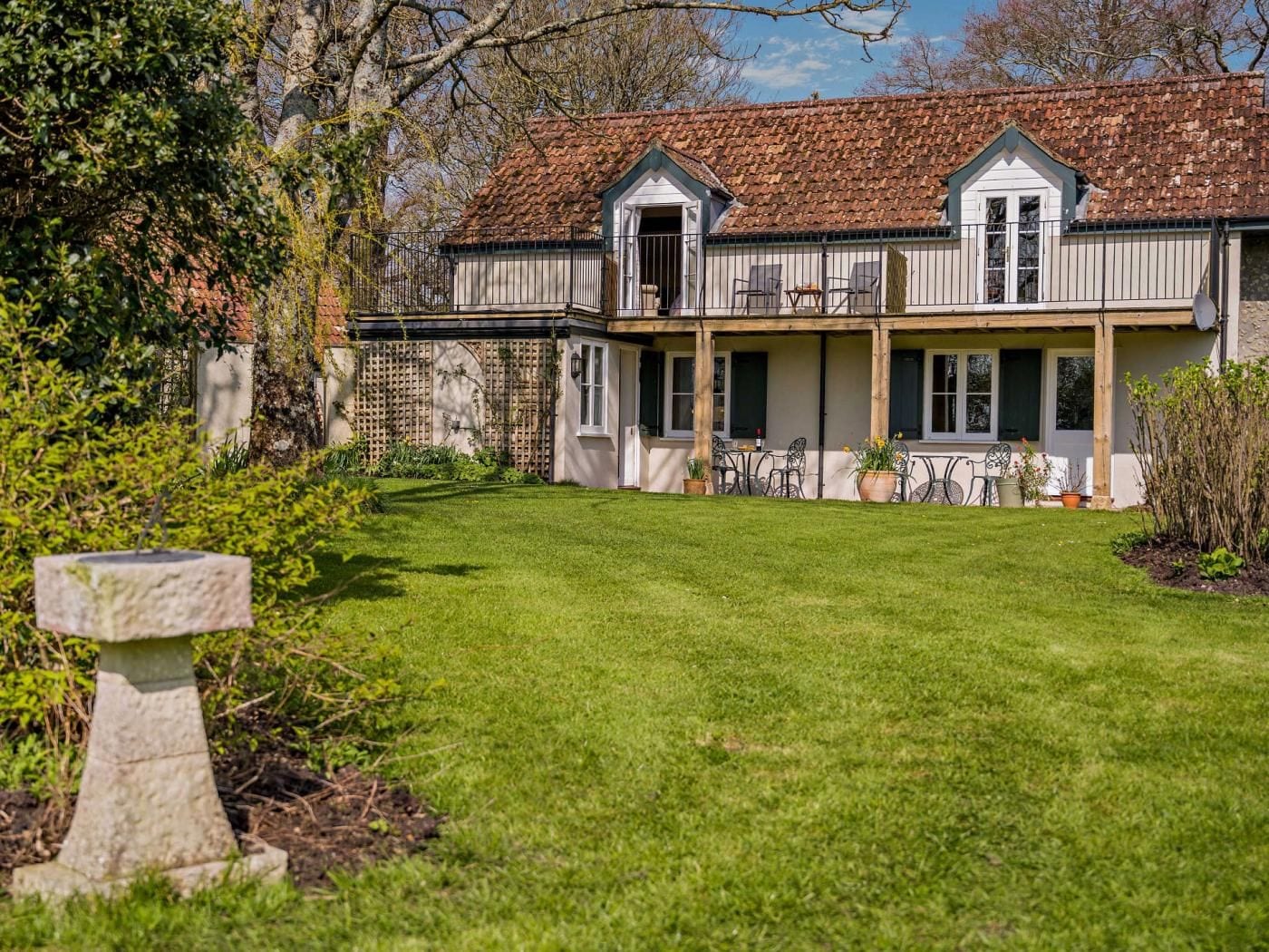 A two-story building with a tiled roof, a fenced garden, and outdoor seating.