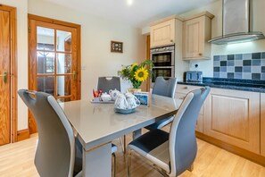 A modern kitchen with a dining table, chairs, a stove, and a tiled backsplash. - 2 Bed in Liskeard (oc-landc) (Duloe)