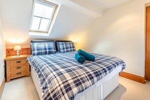 Quarto com uma cama, mesa de cabeceira, abajur, janela e porta.