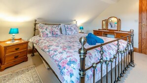 Ein Schlafzimmer mit einem Bett, Nachttischen, einer Kommode, einem Spiegel und einer Tür.