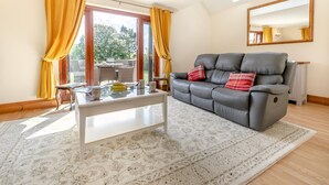 Ein Wohnzimmer mit einer Couch, einem Couchtisch und Blick durch eine Glastür auf einen Außenbereich.