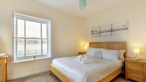 A bedroom with a large window, a bed, bedside tables, and a wall-mounted artwork. - 2 Bed in Bideford (oc-05208) (Appledore)