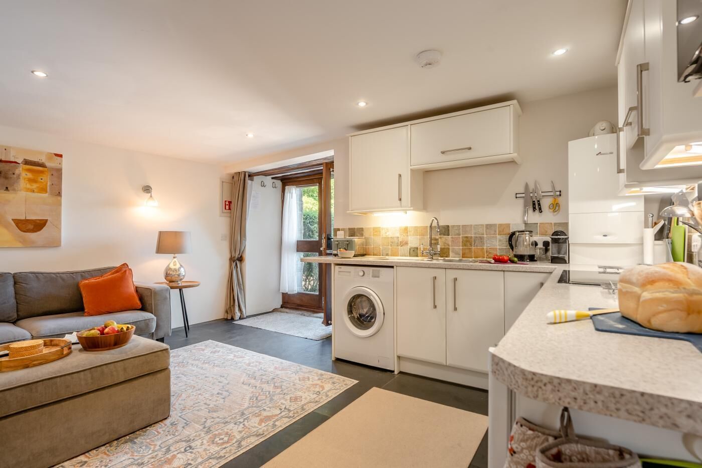 A compact living space with a sofa, a washing machine, and a kitchenette.