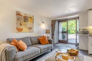 Ein Wohnzimmer mit grauem Sofa, einem Gemälde, einer Lampe und einer Küchenzeile mit einem Toaster.