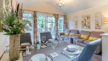 Un coin repas avec une table dressée pour deux personnes, un canapé et un balcon agrémenté de rideaux.