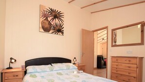 A bedroom with a bed, bedside tables, a dresser, a mirror, and a door leading to another room. - 2 Bed in Redruth (oc-gillo) (Scorrier)