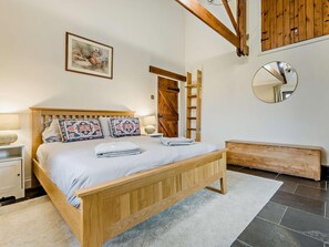 Un dormitorio con cama de madera, una mesita de noche, cómoda, espejo y una puerta con marco de madera.