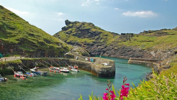 A coastal harbor with boats docked, a stone pier, and a grassy hill in the background. - 3 Bed in Camelford (oc-pendb) (Forrabury and Minster)