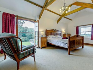 Une chambre à coucher avec un lit en bois, une chaise, une table de chevet et une fenêtre avec des rideaux.