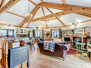 A spacious living area with a high ceiling, wooden beams, a fireplace, a leather sofa, and a dining area with wooden furniture. - 2 Bed in Liskeard (oc-trero) (Menheniot)