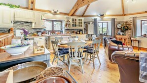 A spacious kitchen with wooden beams, a dining area with chairs, a leather sofa, and a view of the outdoors. - 2 Bed in Liskeard (oc-trero) (Menheniot)
